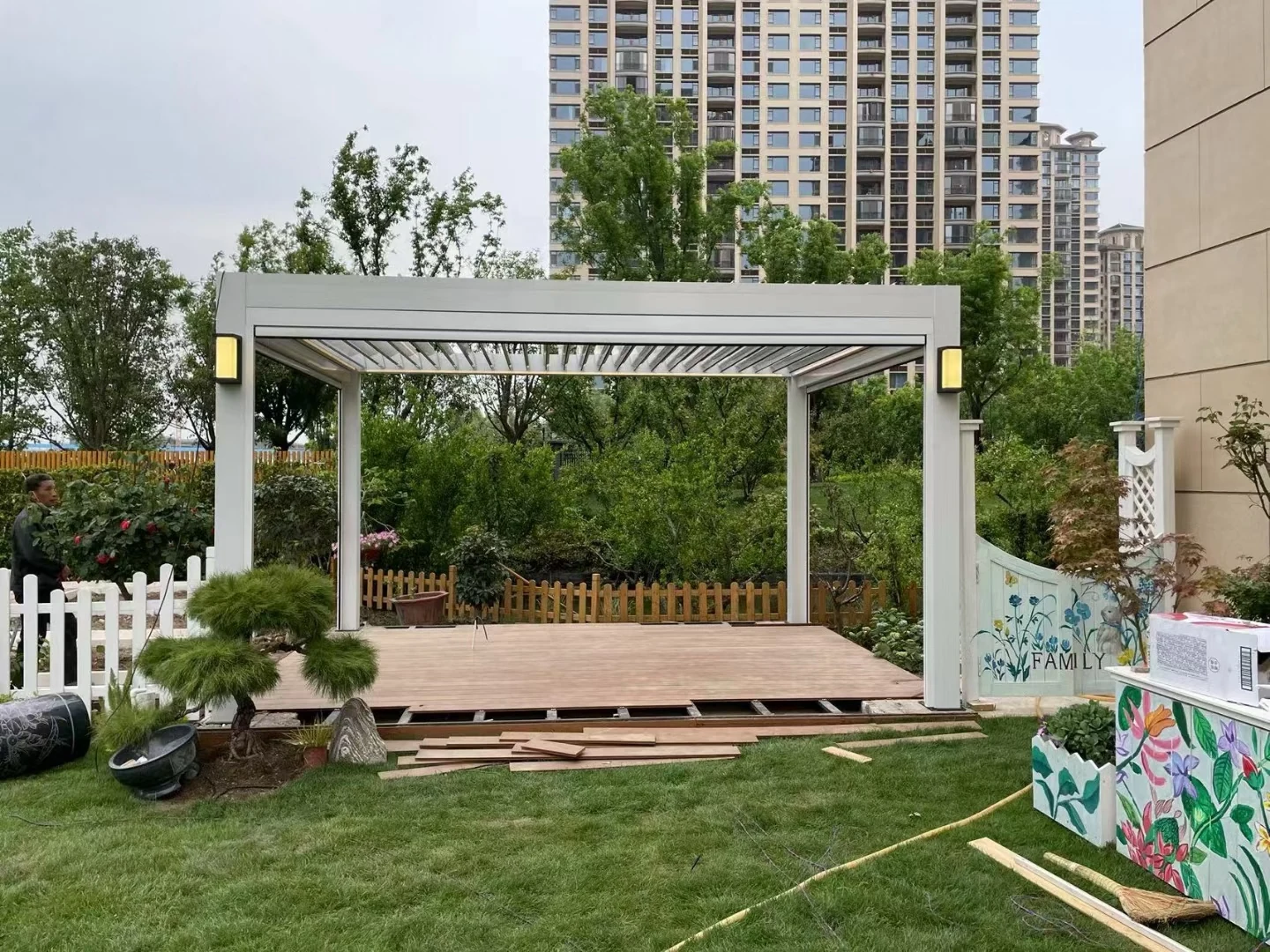 White pergola with open roof louvres and installation materials on site