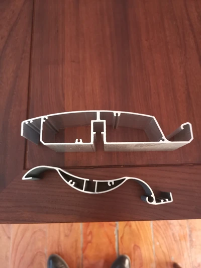 Two aluminium profile section samples on a tabletop.
